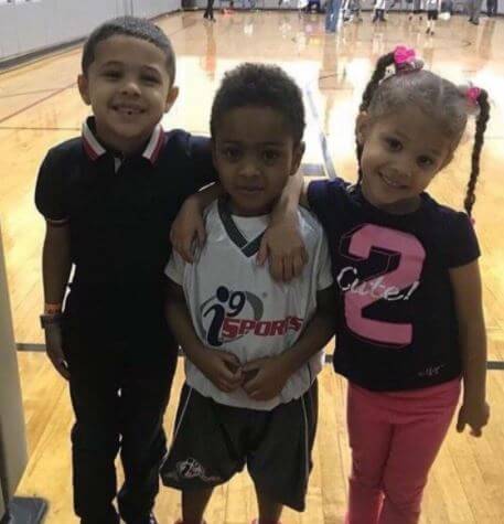 Zayden Banks with his siblings Angelo Banks and Bella Banks in a basketball arena.